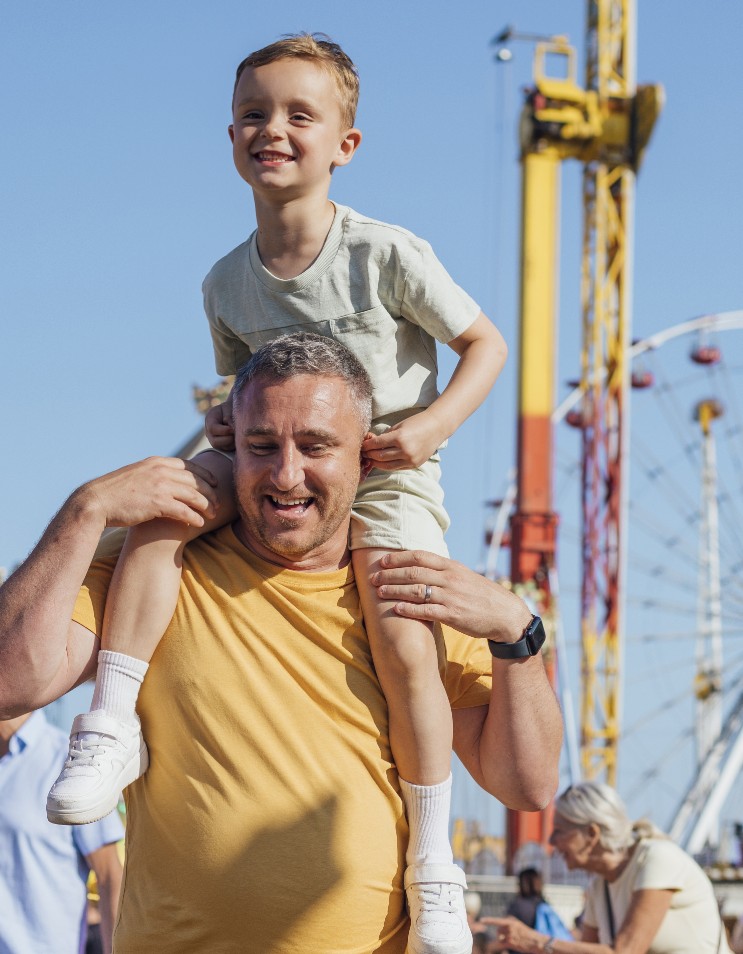 Father with his child on his shoulders walking in a fair ground